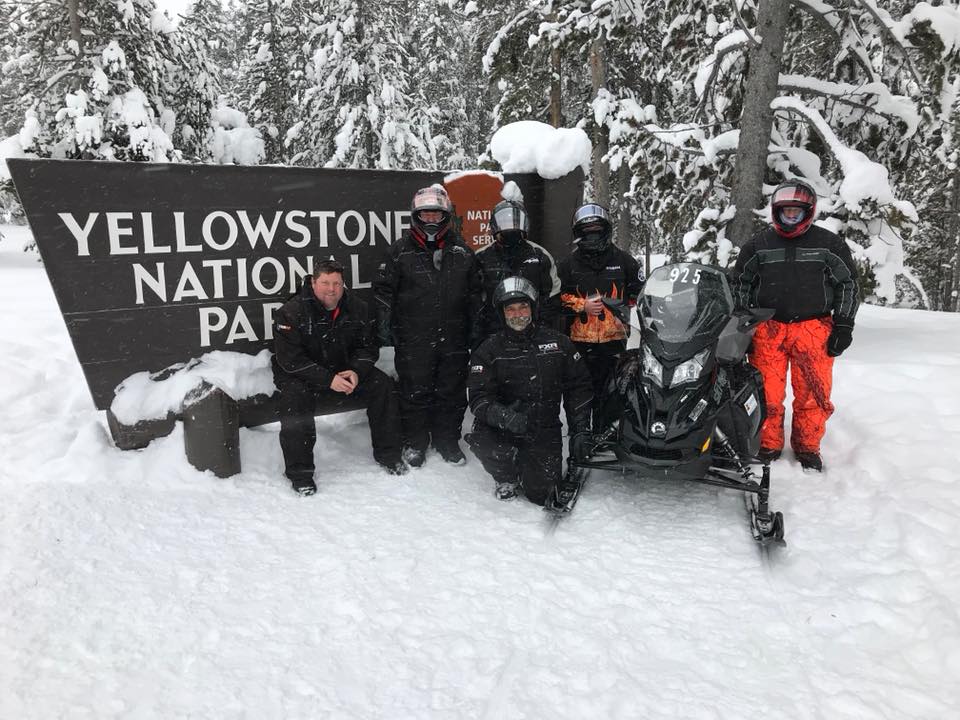 Group in front of Yellowstone National Park sign in the snow